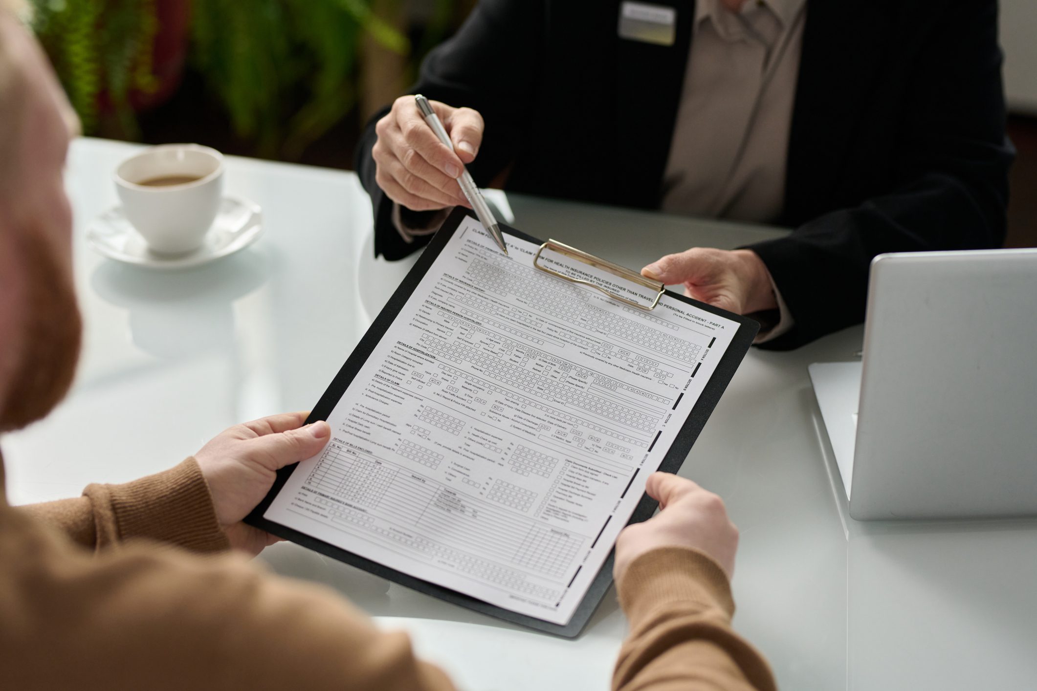 Closeup of insurance advisor handing application form to client during consultation