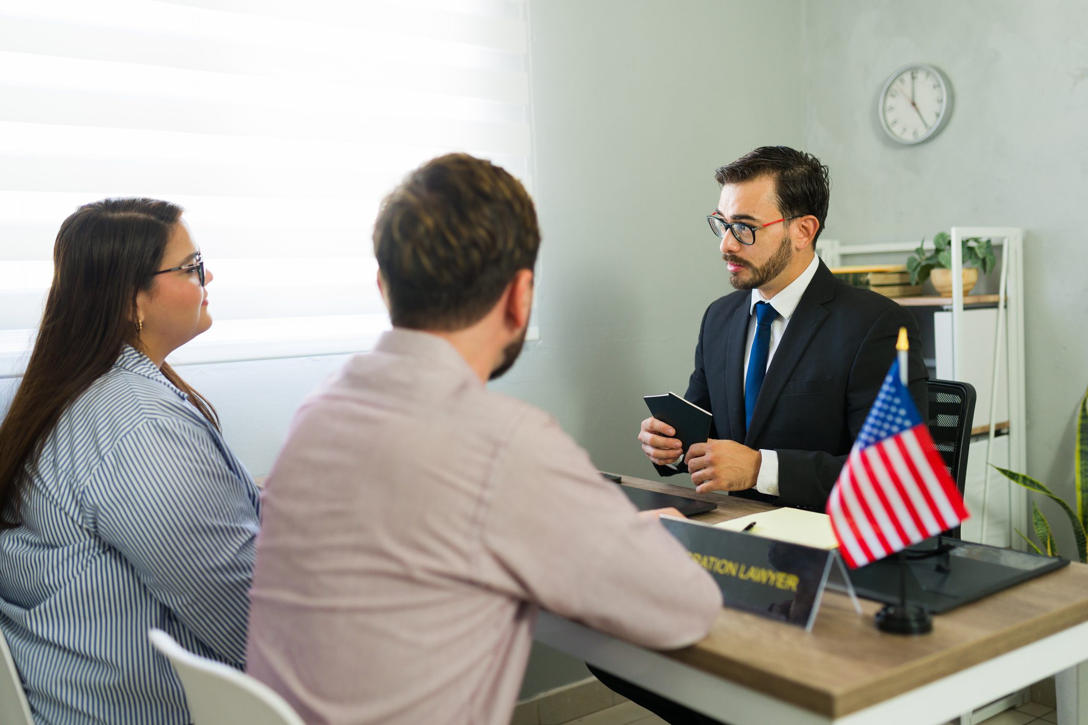 Abogado de inmigración revisando documentos y brindando asesoría legal especializada a una pareja que busca asistencia migratoria en los Estados Unidos.